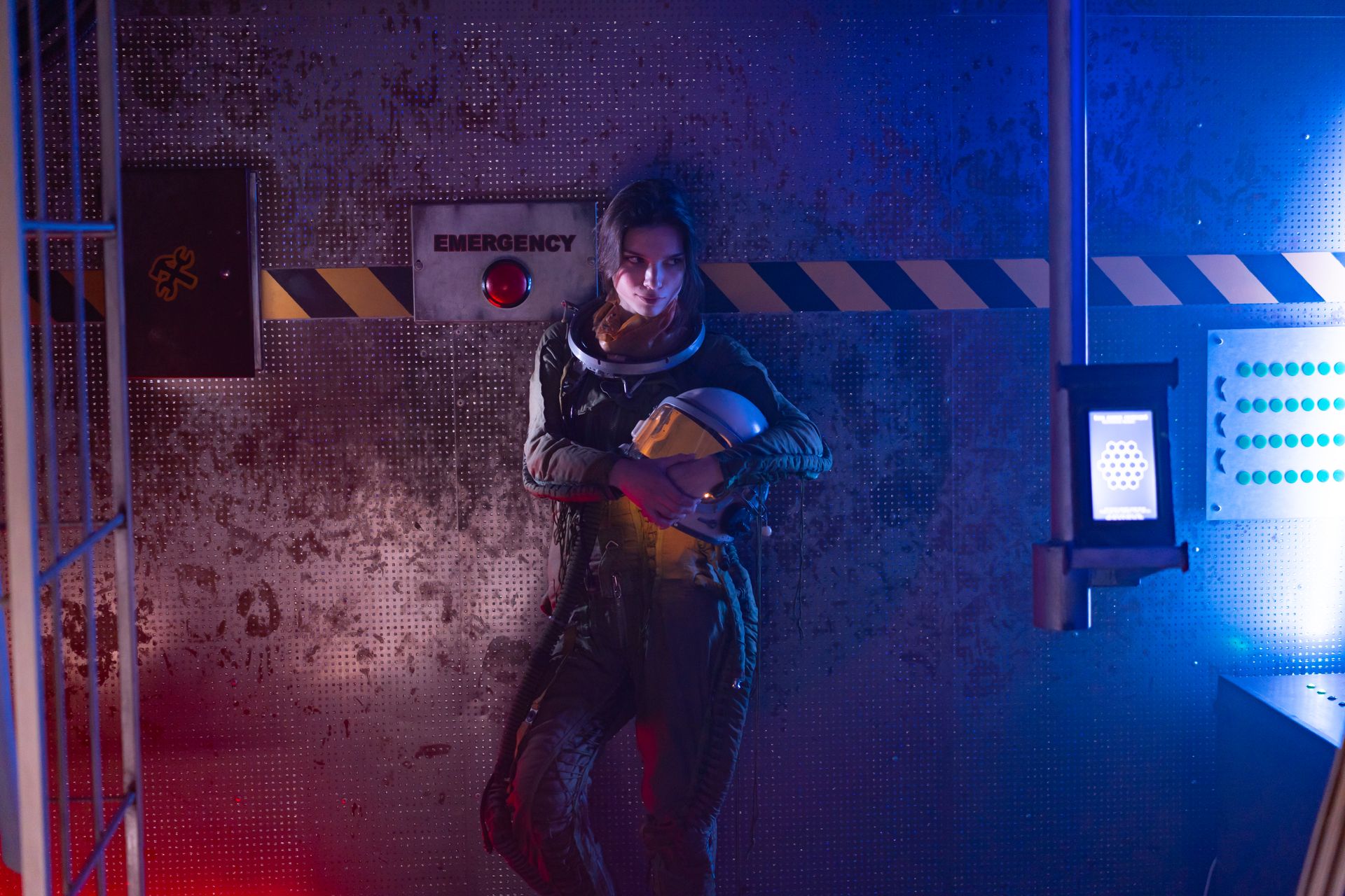 Woman in Spacesuit Standing Near A Wall With Emergency Sign