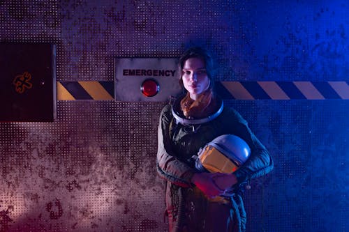 Free Woman In Spacesuit Standing Beside An Emergency Sign Stock Photo