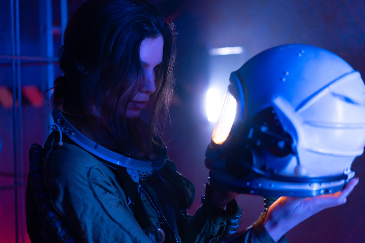 futuristic portrait of a woman in a spacesuit holding a helmet with bl