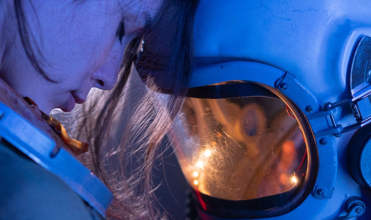 close up of a woman in a reflective moment with a space helmet conveyi