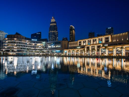 Stunning view of illuminated skyscrapers reflecting on water at Dubai Mall waterfront.