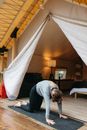 Woman Doing  Cat Pose Yoga Position on the Wooden Floor