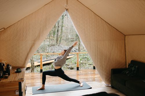 Free Person practicing yoga inside a cozy tent with a view of nature, embodying tranquility and fitness. Stock Photo