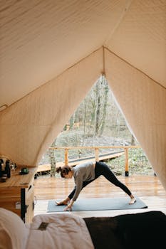 A woman doing yoga inside a tent, embracing a healthy outdoor lifestyle in a serene natural setting.
