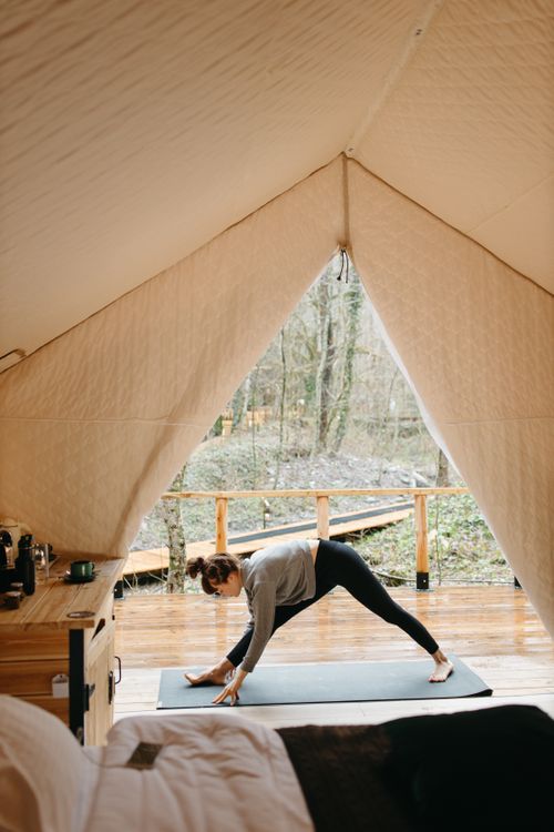 Free A woman doing yoga inside a tent, embracing a healthy outdoor lifestyle in a serene natural setting. Stock Photo
