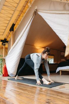 Woman practicing yoga in a cozy glamping tent setting, embracing a healthy lifestyle.