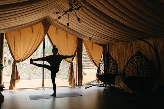 Silhouette of a woman practicing yoga indoors in a glamping tent, promoting flexible and healthy living.