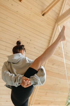 A woman performs a yoga pose indoors, showcasing flexibility and focus.