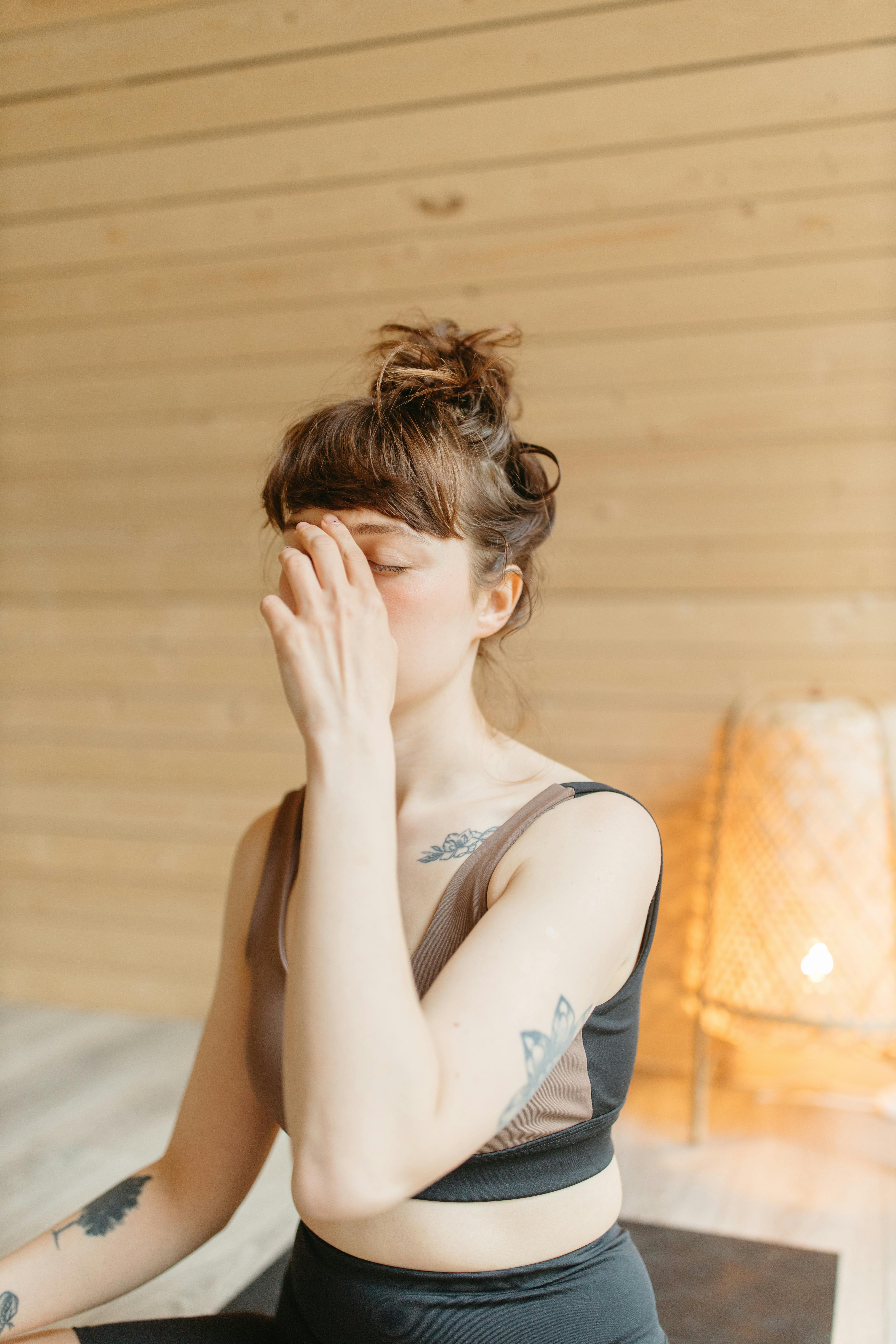 Focused woman practicing yoga breathing technique indoors with natural lighting.