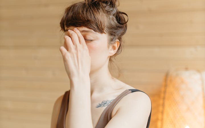 Focused woman practicing yoga breathing technique indoors with natural lighting.