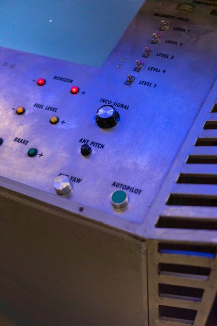 Control panel with blue lighting, buttons, and switches for spacecraft navigation.