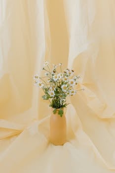 A collection of delicate daisies arranged in a beige vase set against a soft, pastel backdrop for a serene visual.