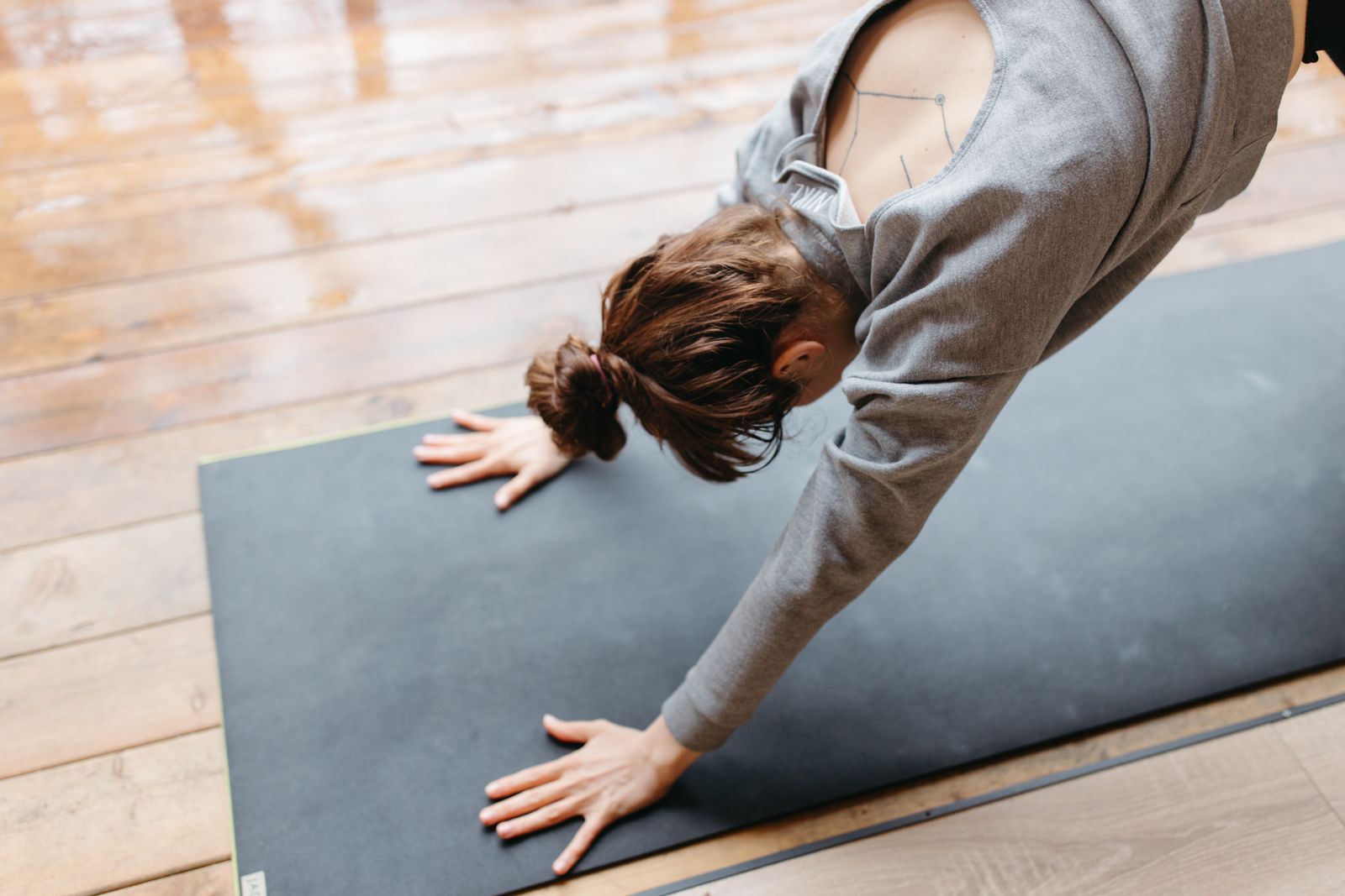 Young woman practicing yoga on a mat indoors on a wooden floor during a daily yoga challenge