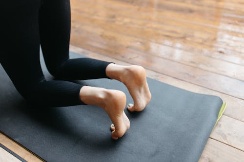 Free Woman in Black Leggings Kneeling on Gray Yoga Mat Stock Photo