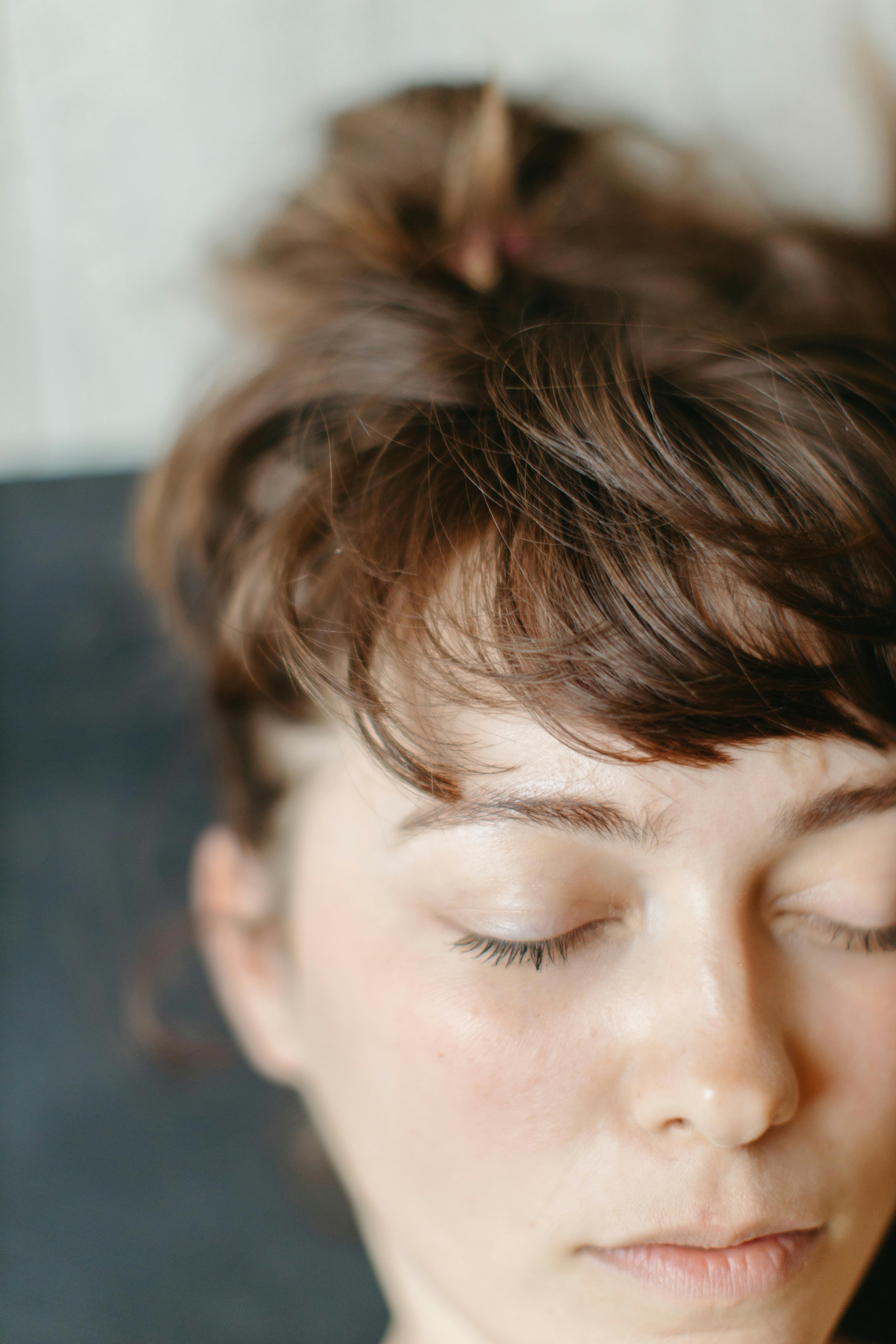 Close-up of woman's relaxed face with eyes closed, serene expression in soft lighting