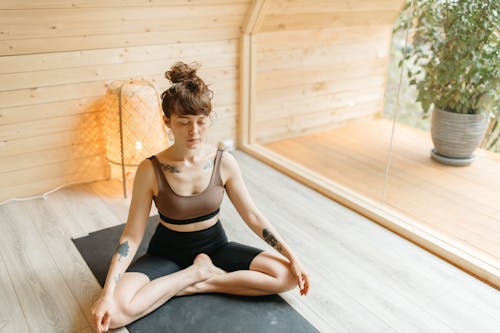 Free Tattooed Woman in Activewear Meditating Stock Photo