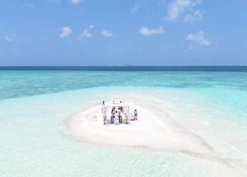 A beautiful wedding ceremony on a secluded sandbank in the Maldives, perfect for a romantic getaway.