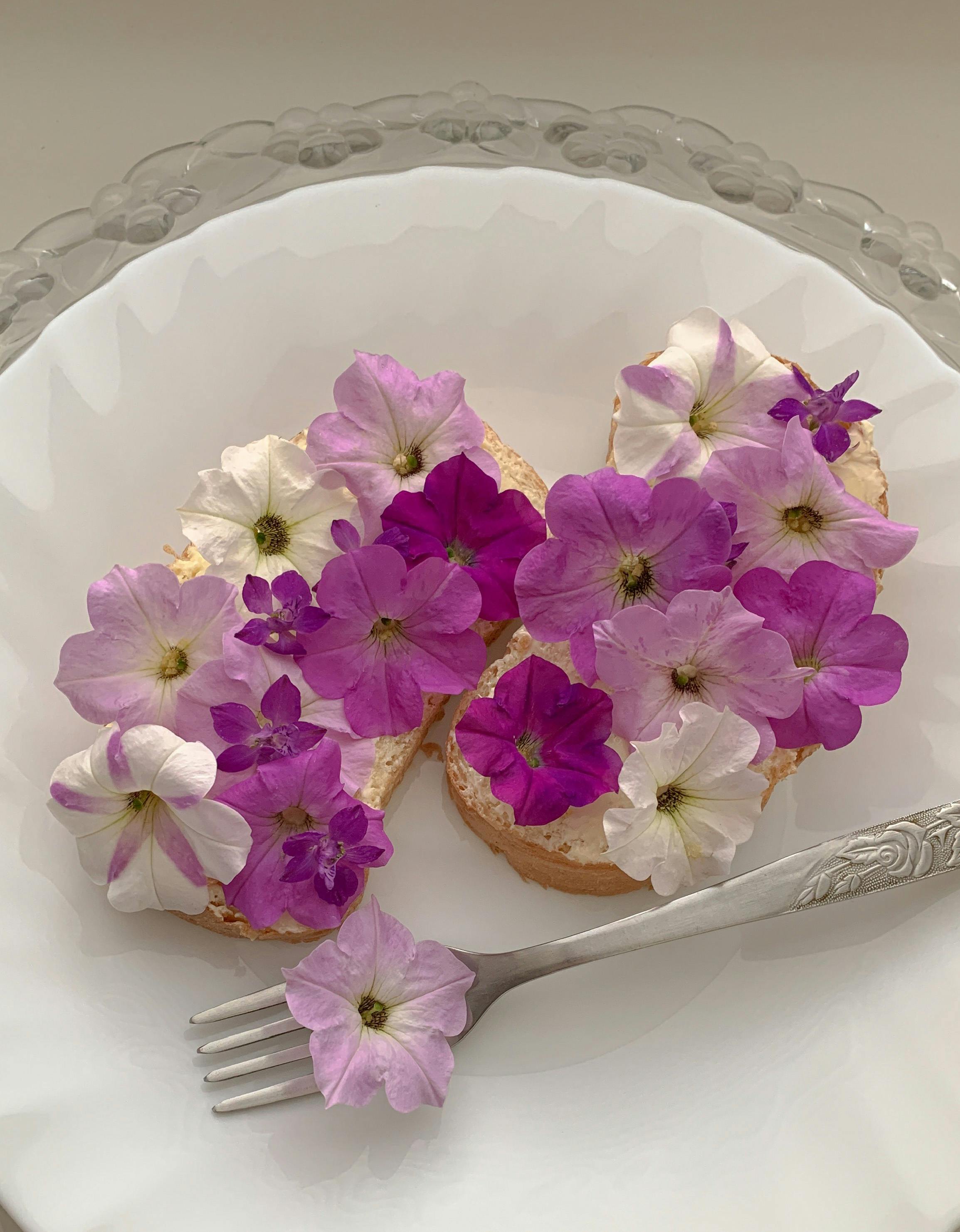 Bread with purple and white flowers as garnish, styled on a white plate with a silver fork.
