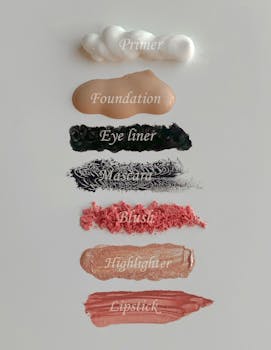Stylish flat lay of cosmetics swatches including primer, foundation, eyeliner, mascara, blush, highlighter, and lipstick.
