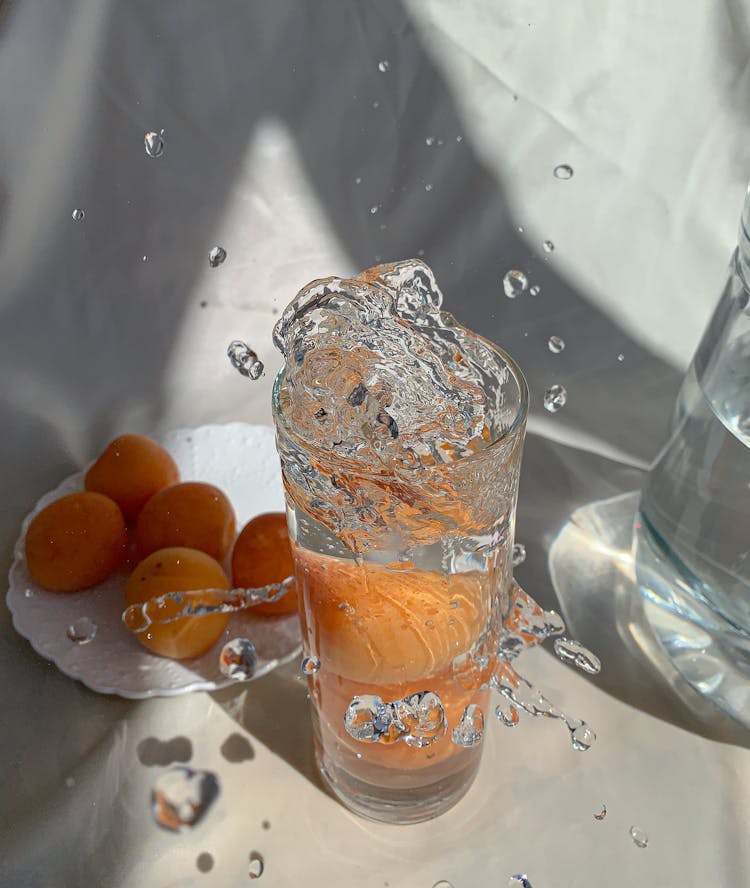 Photo Of An Apricot Falling In A Glass Of Water