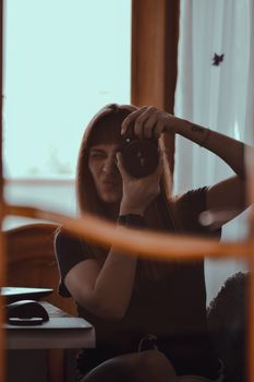 A woman takes a photograph with a DSLR camera indoors, capturing a creative portrait.