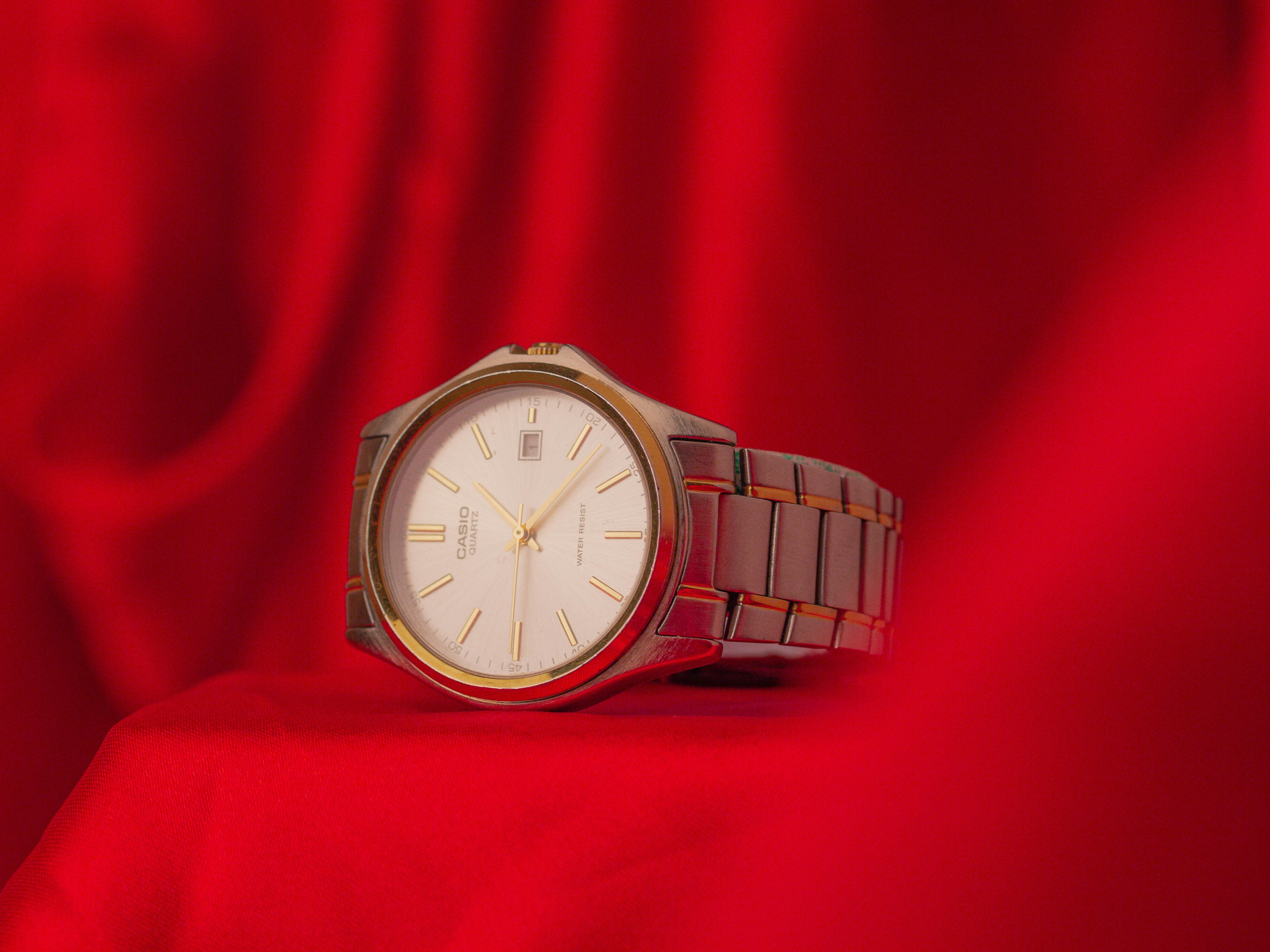 a silver watch with golden details on a red fabric