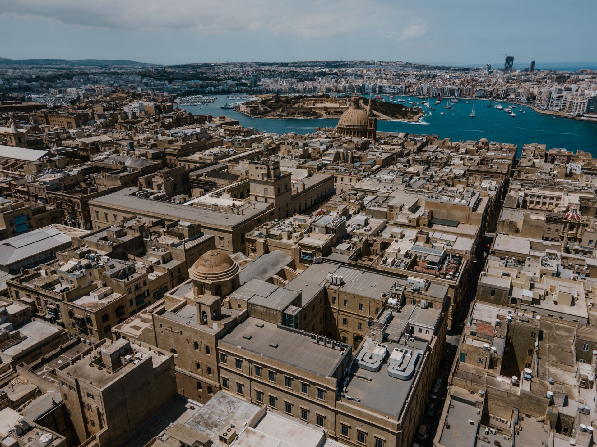 Aerial view of Valletta, Malta, its honey-colored limestone rooftops and domes above the harbour