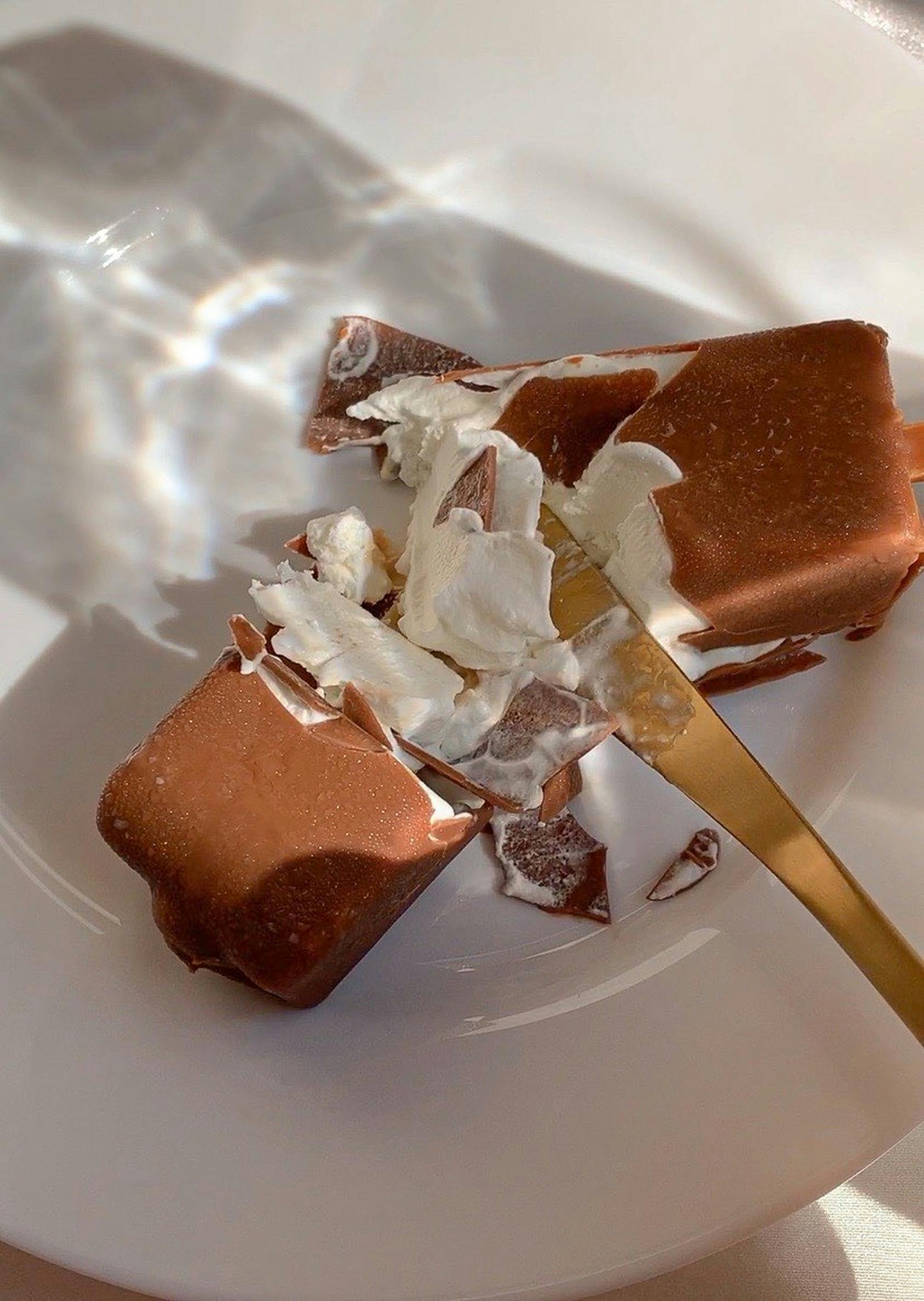 Close-up of a delicious chocolate and cream dessert on a white plate, captured in warm lighting.