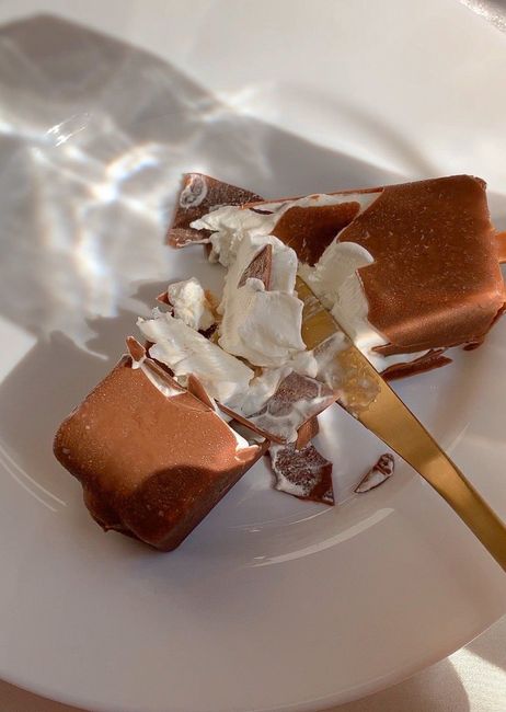 Close-up of a delicious chocolate and cream dessert on a white plate, captured in warm lighting.