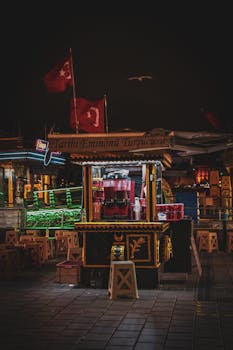 Illuminated food cart in Istanbul at night with Turkish flags.