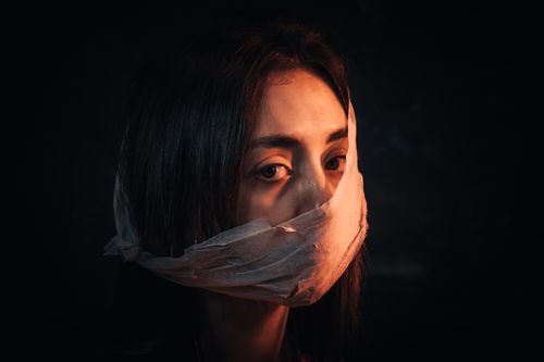 Free A woman with her face covered in fabric portrays silence and introspection against a dark background. Stock Photo