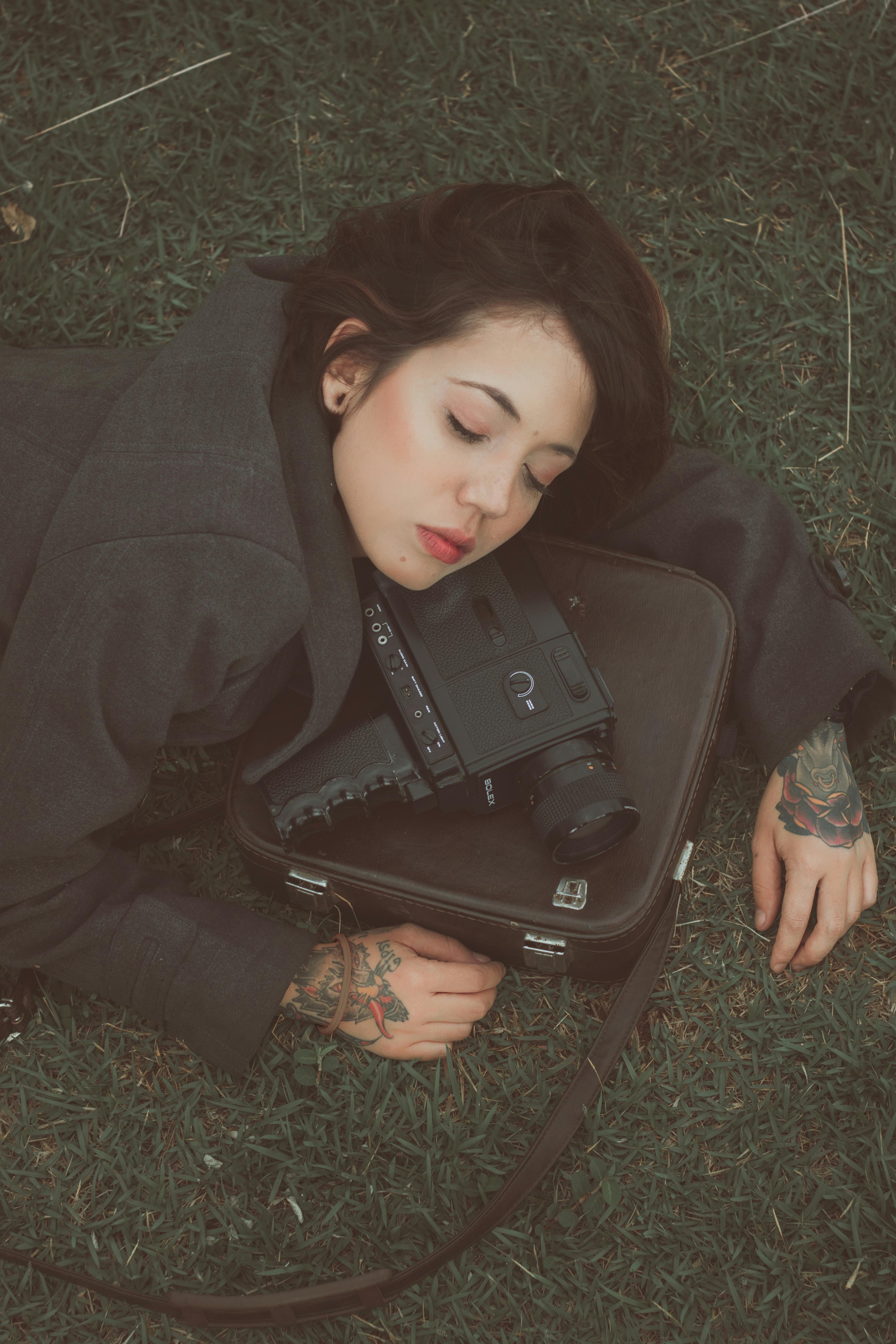 tattooed woman with retro video camera lying on meadow