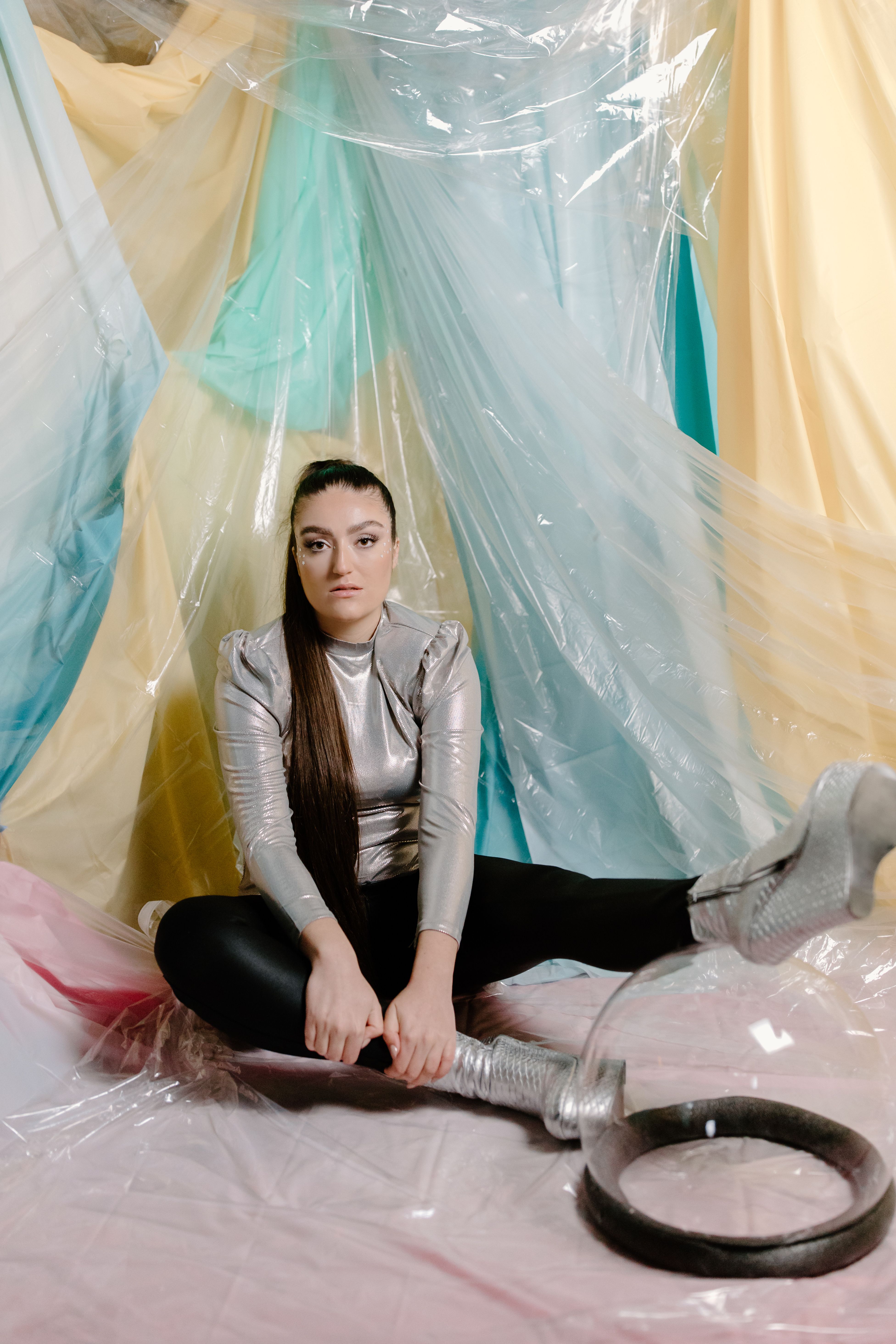 Woman in a silver futuristic outfit with a colorful abstract background.