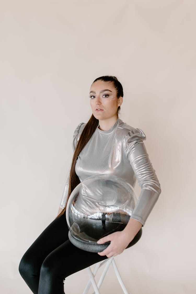 A Woman In A Gray Top Holding A Glass Helmet