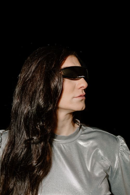 Free Portrait of a woman in a silver futuristic outfit with dark sunglasses against a black background. Stock Photo