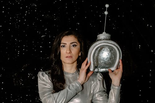 Woman in Space Suit Holding a Space Helmet 