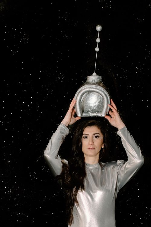 Free Space-themed fashion shoot featuring a woman in a futuristic outfit holding a helmet. Stock Photo