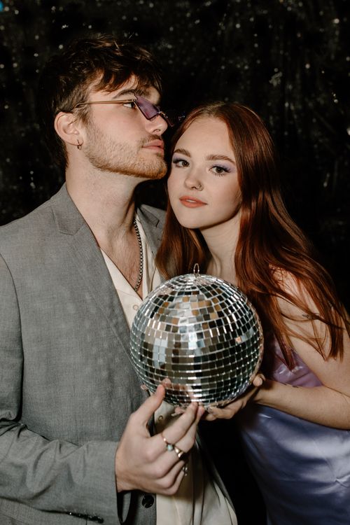 Free Stylish young couple in a studio with a disco ball, showcasing modern party vibes. Stock Photo