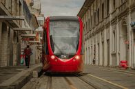 A vibrant red tram navigates the historical streets of Cuenca, Ecuador.
