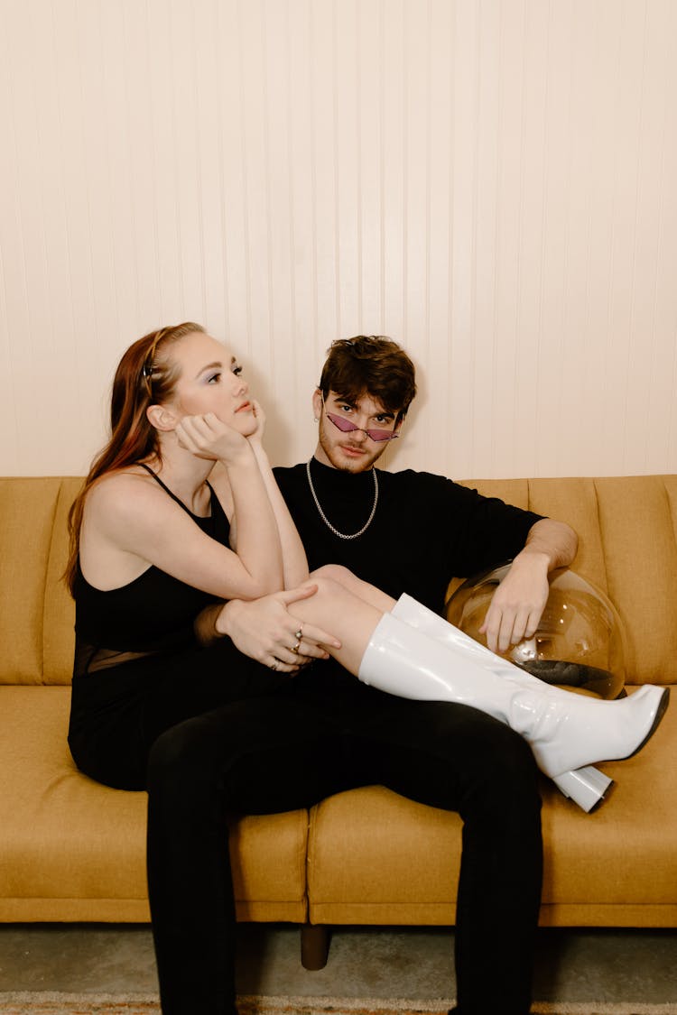 Woman In Black Spaghetti Strap Top And A Man In Black Clothes Sitting On A Couch