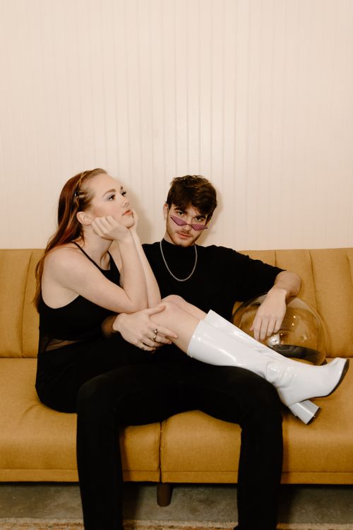 Free Stylish couple posing on a vintage sofa, capturing modern fashion and relaxed vibes indoors. Stock Photo