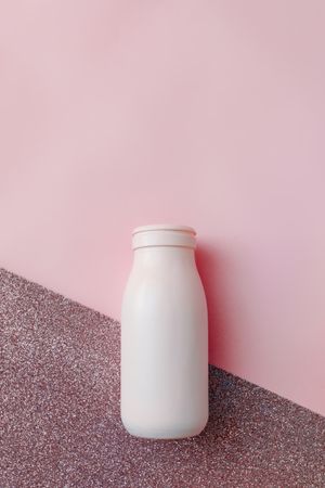Publicité flacon cosmétique sur fond rose, format vertical