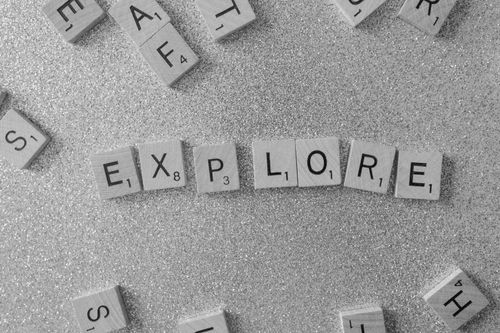 Free Ambient shot of Scrabble tiles spelling 'Explore' on a glittery surface. Stock Photo