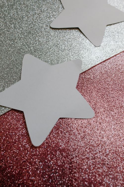 Free White star-shaped cutouts on a glittery silver and pink background. Stock Photo