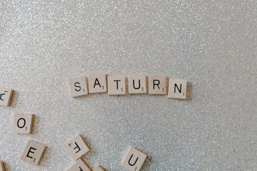 Scrabble tiles forming the word SATURN on a sparkling glitter background, space theme.