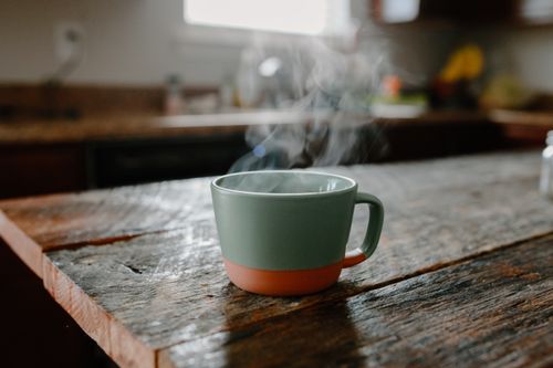 Free A warm, steaming cup of coffee on a rustic wooden table, creating a cozy kitchen vibe. Stock Photo