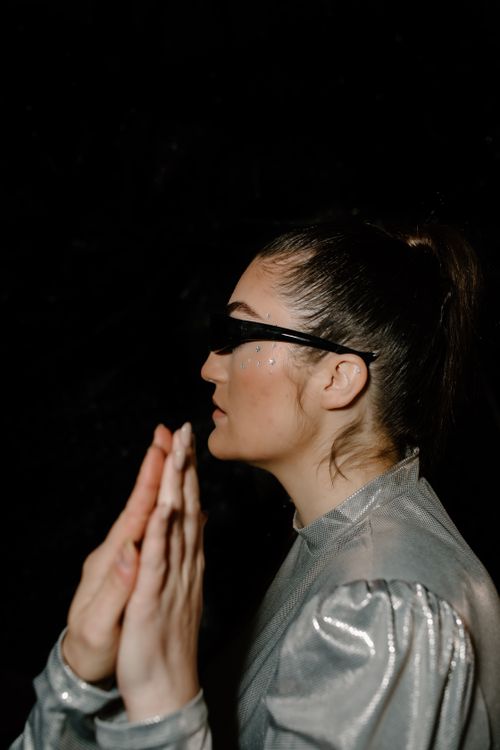 Free Profile of a woman in futuristic silver attire, wearing sunglasses, set against a dark background. Stock Photo