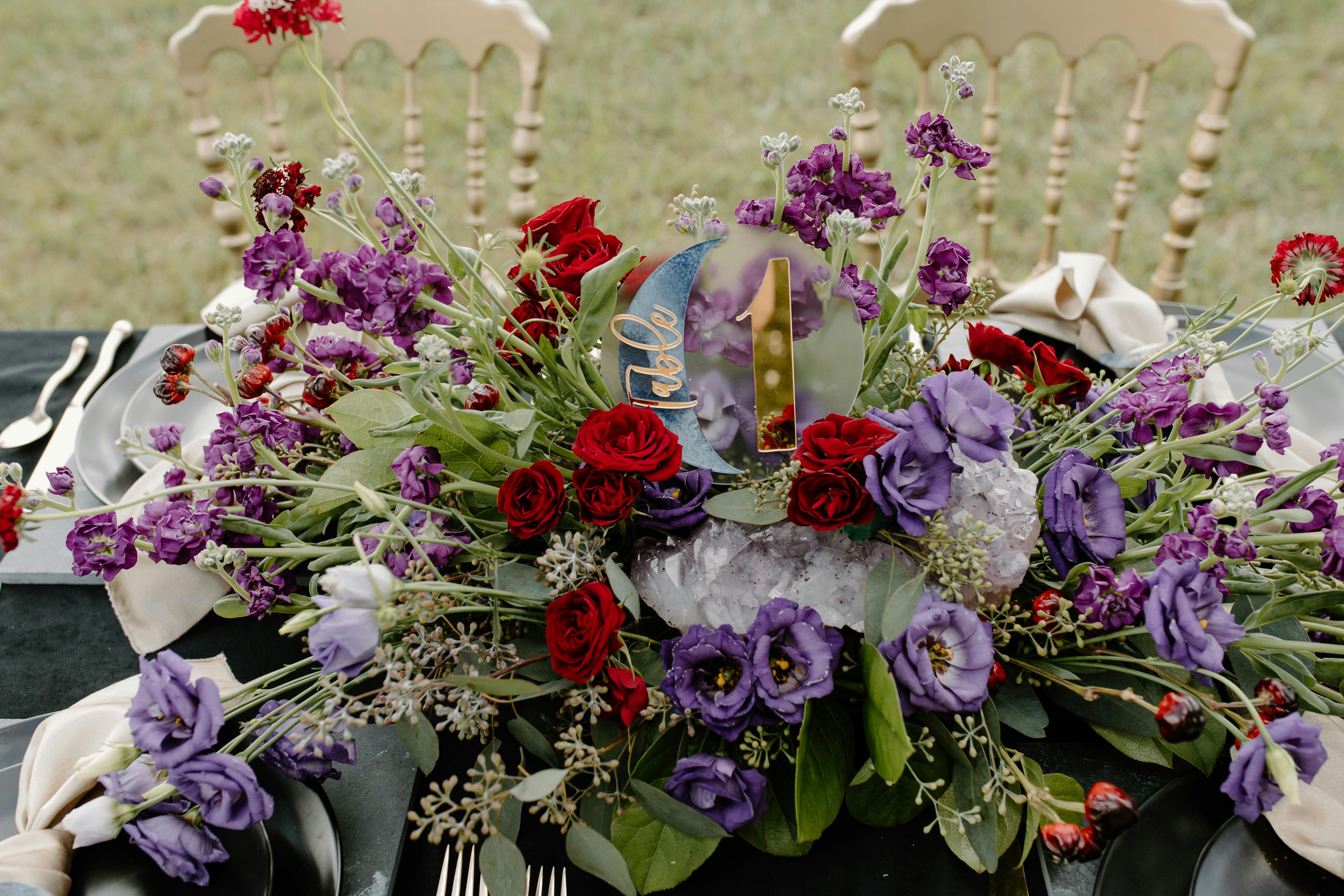 A stunning floral arrangement with purple and red flowers as a wedding table centerpiece.