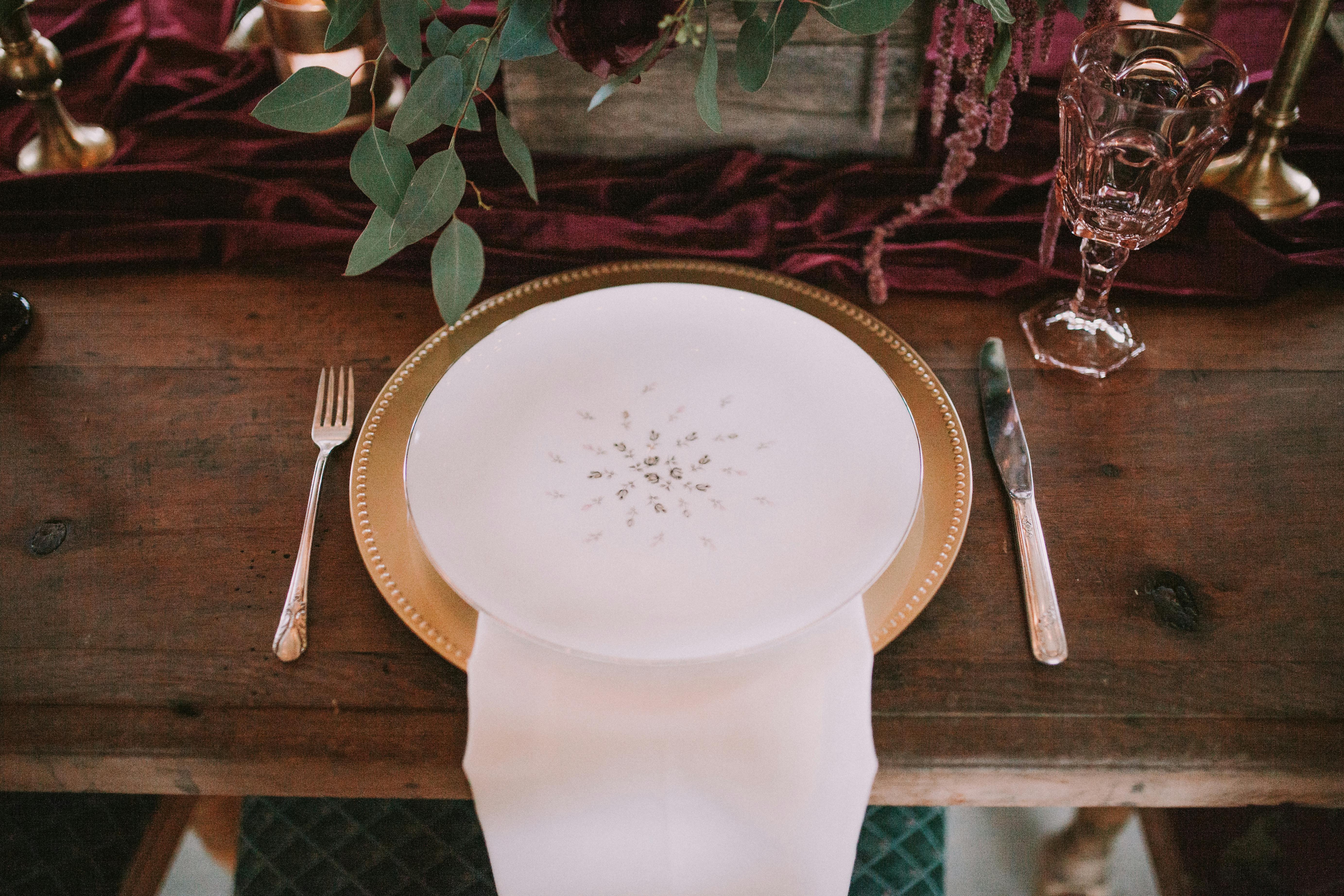 A beautifully arranged table setting featuring a gold charger plate and floral decor.