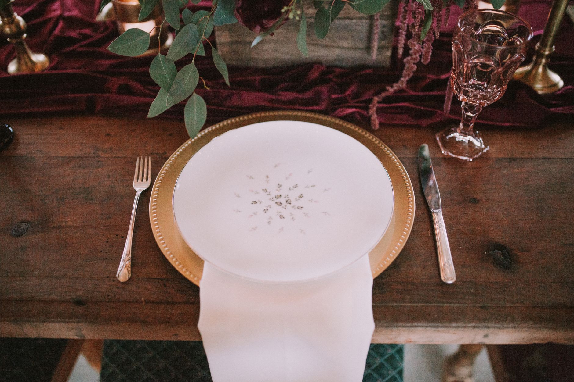 A beautifully arranged table setting featuring a gold charger plate and floral decor.